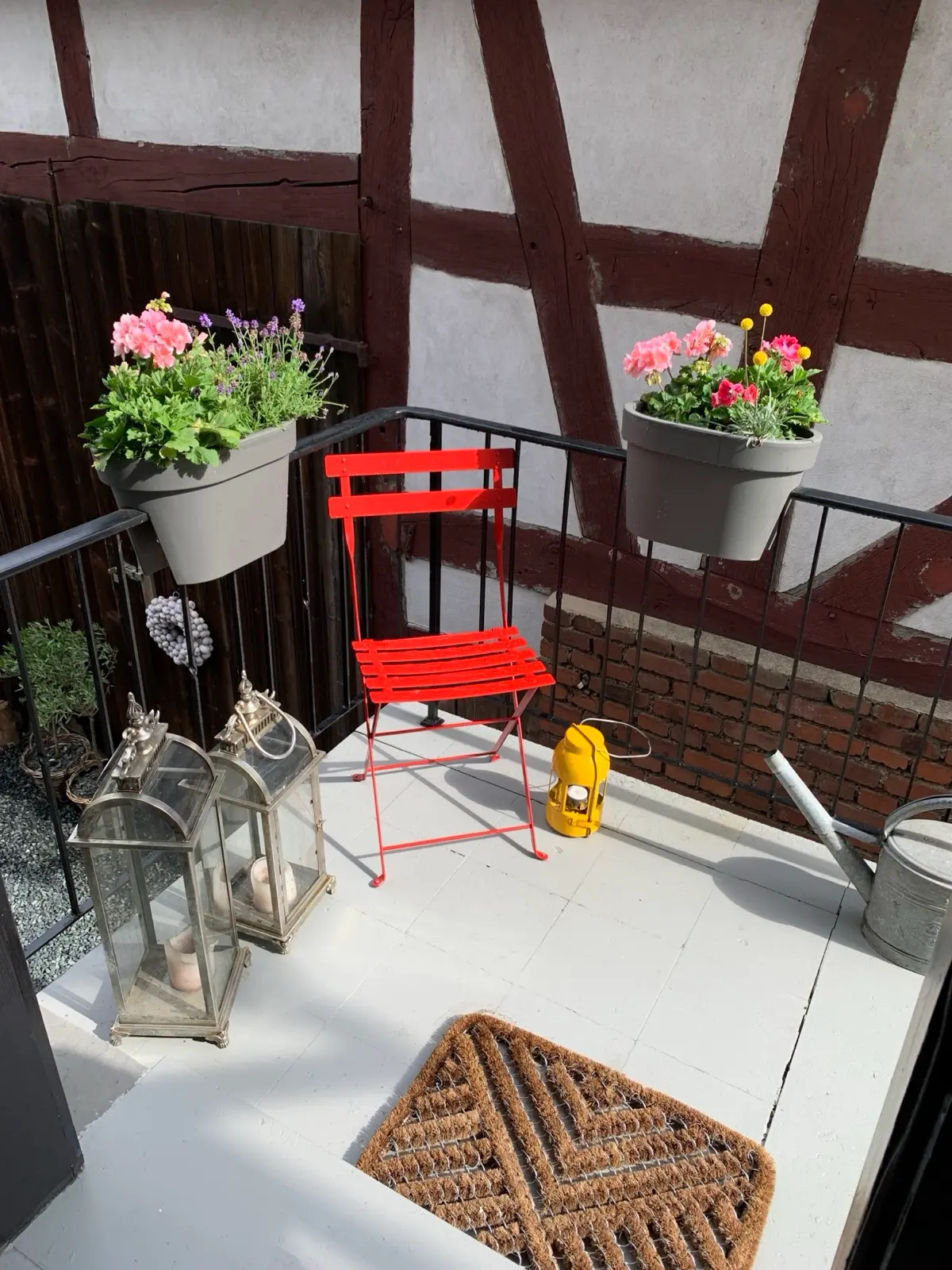 Balkon mit rotem Klappstuhl und Blumenkästen am Rosehill Cottage 1699 – Sommer im Lahn-Dill-Bergland
